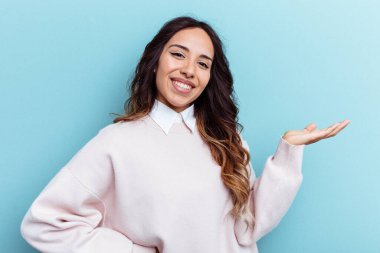 Mavi arka planda izole edilmiş genç Meksikalı kadın hoş bir yüz ifadesi sergiliyor..