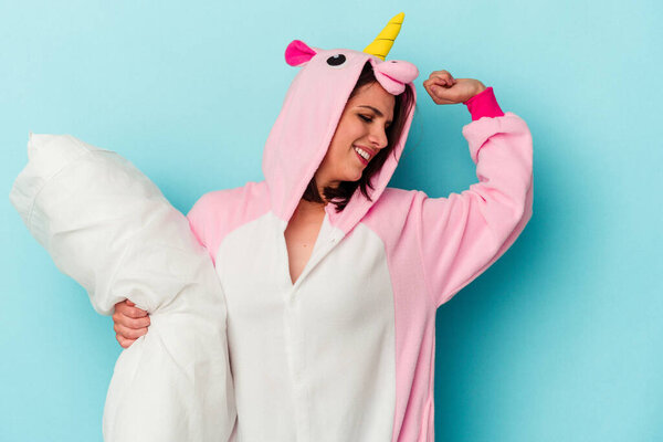 Young caucasian woman wearing an unicorn pajama isolated on blue background