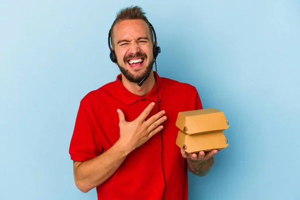 Young Caucasian Delivery Man Tattoos Holding Burgers Isolated Blue Background — Stock Photo, Image