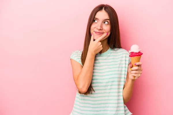 Молодая Белая Женщина Держащая Мороженое Розовом Фоне Смотрит Сторону Сомнительным — стоковое фото
