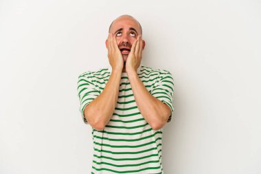 Genç kel adam, beyaz arka planda yalnız başına sızlanıyor ve ağlıyordu..