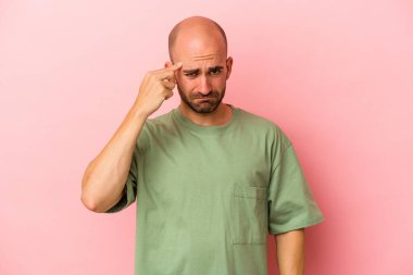 Pembe arka planda izole edilmiş beyaz saçlı genç bir adam şakağı parmağıyla işaret ediyor, düşünüyor ve bir göreve odaklanıyor..