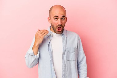 Pembe arka planda soyutlanmış beyaz kel bir adam bir şeye gülüyor, elleri ile ağzını kapatıyor..