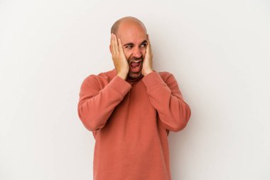 Genç kel adam beyaz arka planda izole edilmiş kulakları elleriyle kapatıyor yüksek sesli sesler duymamaya çalışıyor..