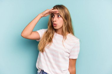 Mavi arka planda soyutlanmış, elini alnına koyan beyaz, sarışın genç bir kadın..