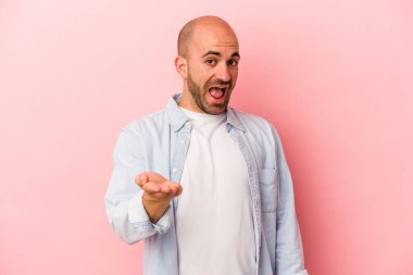 Beyaz saçlı genç adam pembe arka planda izole edilmiş. Kameraya doğru elini uzatarak selam veriyor..