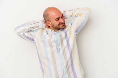 Genç kel adam beyaz arka planda izole edilmiş. Kendine güveniyor, elleri başının arkasında..