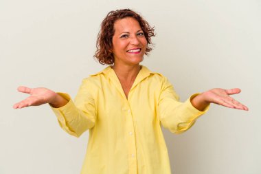 Beyaz arka planda izole edilmiş orta yaşlı Latin kadın kollarıyla ölçeği belirliyor, mutlu ve kendinden emin hissediyor..