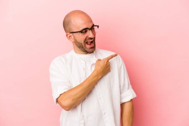 Pembe arka planda soyutlanmış genç, beyaz, kel bir adam gülümseyen, neşeli ve keyifli görünüyor..