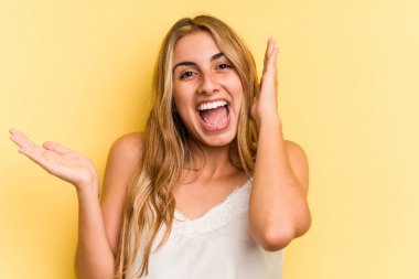 Sarı arka planda izole edilmiş beyaz, genç bir kadın avuç içinde fotokopi alanı tutuyor, el üstünde tutuyor. Şaşırmış ve mutlu..