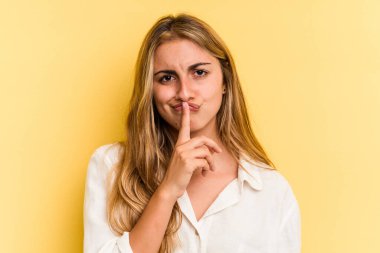 Sarışın, sarı arka planda izole edilmiş genç, beyaz bir kadın. Düşünüyor, düşünüyor, düşünüyor, hayal kuruyor..