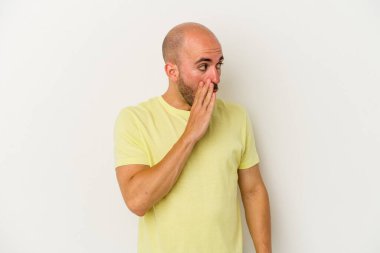 Genç kel adam beyaz arka planda izole edilmiş. Gördüğü bir şey yüzünden şok oluyor..