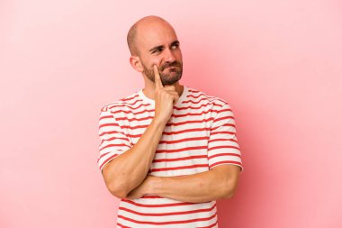 Kafkasyalı genç kel adam pembe arka planda izole edilmiş. Bir strateji planlıyor, bir iş yolu düşünüyor..