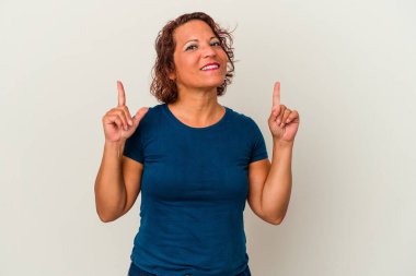 Beyaz arka planda izole edilmiş orta yaşlı Latin kadın iki ön parmağı da boş bir alan gösteriyor..