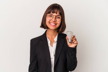 Beyaz arka planda izole edilmiş ampulü tutan genç melez iş kadını mutlu, güler yüzlü ve neşeli..