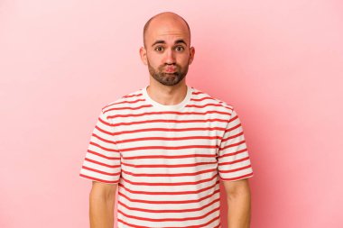 Pembe arka planda izole edilmiş beyaz kel bir adam yanakları patlatıyor, yorgun bir ifadesi var. Yüz ifadesi kavramı.