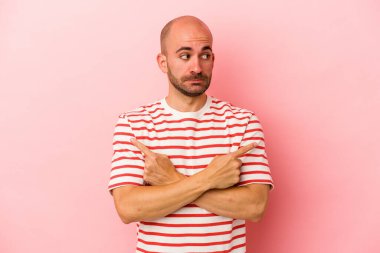 Pembe arka plan noktalarında izole genç, beyaz kel adam, iki seçenek arasında seçim yapmaya çalışıyor.