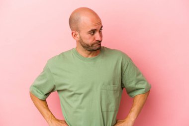 Pembe arka planda soyutlanmış, kafası karışmış, kuşkulu ve kendinden emin olmayan genç beyaz bir adam..