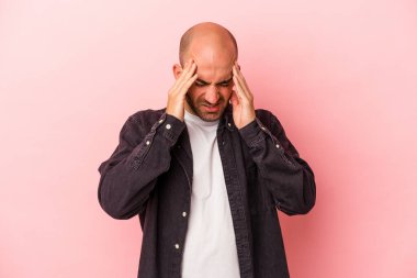 Genç beyaz kel adam pembe arka planda izole edilmiş tapınaklara dokunuyor ve baş ağrısı çekiyor..