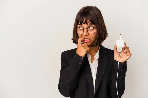 若い混合レースビジネス女性は 白い背景に隔離された携帯電話の充電器を保持肩とオープン目が混乱します — ストック写真