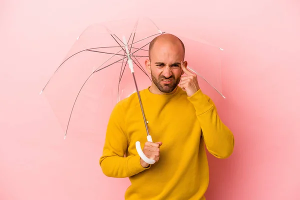 年轻的高加索秃头男子拿着雨伞 与粉红背景隔离 用食指表示失望的姿态 — 图库照片