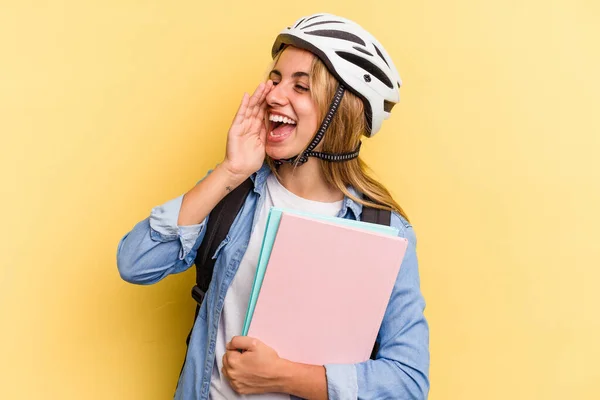 若いですCaucasian学生女性身に着けていますAバイクヘルメット隔離上の黄色の背景叫びと保持手のひら近くにオープン口 — ストック写真