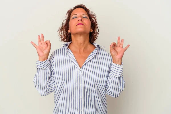 Beyaz arka planda izole edilmiş orta yaşlı Latin kadın yoğun bir günün ardından rahatlıyor, yoga yapıyor..
