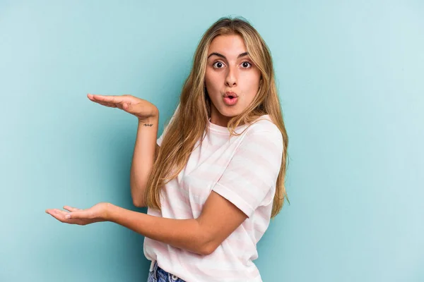 Jovem Mulher Loira Caucasiana Isolado Fundo Azul Chocado Surpreso Segurando — Fotografia de Stock