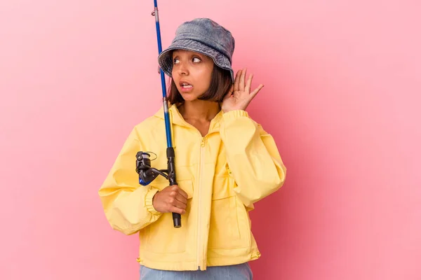 ピンクの背景に隔離された釣りを練習している若い混合人種の女性はゴシップを聞いてみる — ストック写真