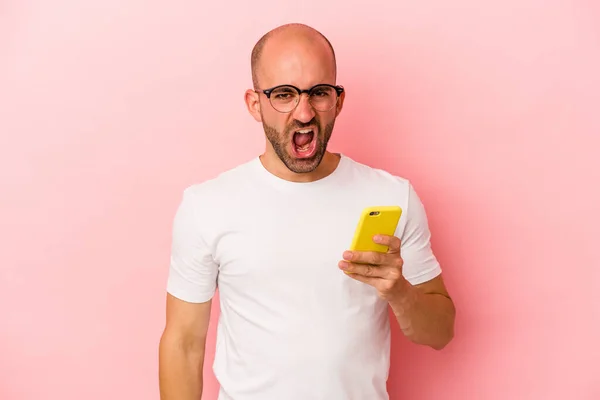 Młody Biały Łysy Człowiek Trzyma Telefon Komórkowy Odizolowany Różowym Tle — Zdjęcie stockowe