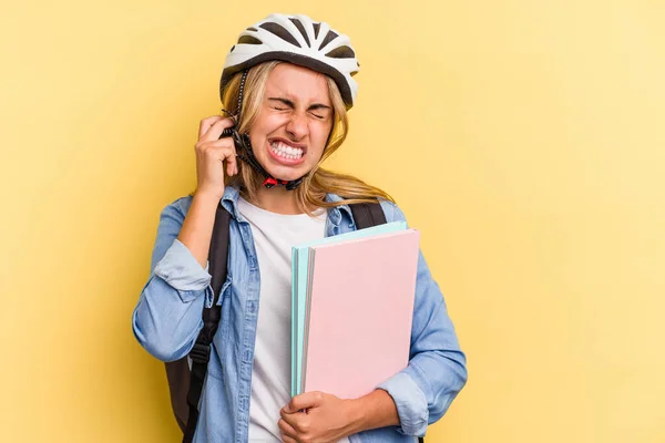 若いですCaucasian学生女性身に着けていますAバイクヘルメット絶縁上の黄色の背景カバー耳で手 — ストック写真