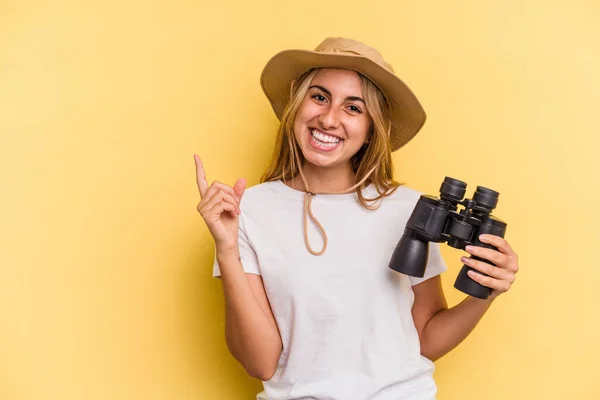 Young Caucasian Woman Holding Binoculars Isolated Yellow Background Smiling Pointing — Stock Photo, Image