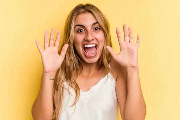 年轻的高加索金发女子在黄色背景下孤立无援 得到了一个愉快的惊喜 兴奋地举起双手 — 图库照片