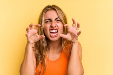 Sarı arka planda izole edilmiş beyaz tenli genç kadın gergin elleriyle çığlık atıyor..