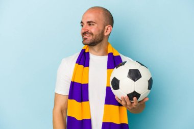 Mavi arka planda izole edilmiş atkı takan genç, kel bir adam gülümseyen, neşeli ve keyifli bir tarafa bakıyor..