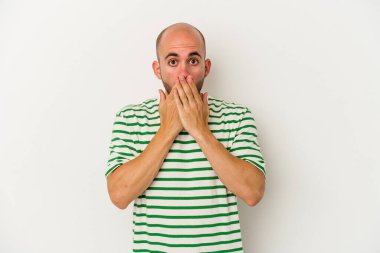 Beyaz arka planda izole edilmiş genç kel adam şok olmuş, ağzı ellerle kaplanmış, yeni bir şey keşfetmeye hevesli..