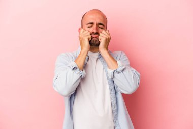 Kafkasyalı kel bir adam pembe arka planda izole edilmiş sızlanıyor ve ağlıyordu..