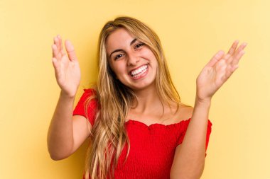 Sarı arka planda izole edilmiş beyaz, genç bir kadın hoş bir yüz ifadesi sergiliyor..