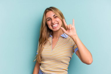 Mavi arka planda izole genç beyaz kadın boynuzlarını bir devrim konsepti olarak gösteriyor..