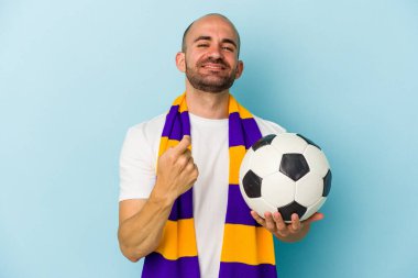 Mavi arka planda izole edilmiş atkı takan genç ve kel bir adam sanki seni davet ediyormuş gibi parmağıyla işaret ediyor..