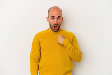 Beyaz arka planda soyutlanmış genç kel bir adam parmağını göstererek şaşırdı, geniş bir gülümsemeyle..