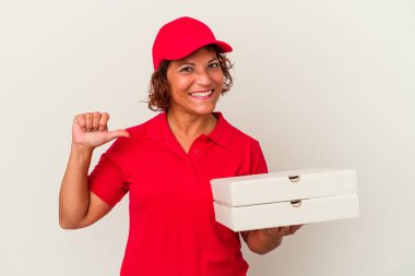 Beyaz arka planda izole edilmiş pizzaları alan orta yaşlı teslimatçı kadın gururlu ve kendinden emin hissediyor, örnek olarak..
