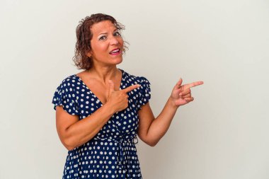 Beyaz arka planda izole edilmiş orta yaşlı Latin kadın işaret parmağıyla fotokopi alanını işaret ederek şok oldu..