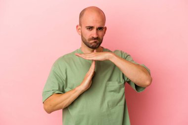 Pembe arka planda izole edilmiş beyaz, kel bir adam bir mola hareketi gösteriyor..