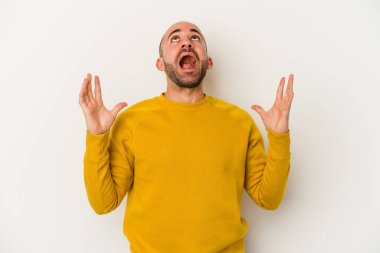 Genç kel adam beyaz arka planda izole edilmiş gökyüzüne haykırıyor, yukarı bakıyor, hayal kırıklığına uğramış..