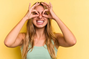 Sarışın, sarı arka planda izole edilmiş genç, beyaz bir kadın heyecanlı..