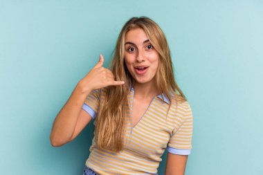 Mavi arka planda izole edilmiş beyaz, genç bir kadın bir şeye gülüyor, ağızlarını ellerle kapatıyor..