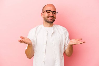 Pembe arka planda soyutlanmış beyaz saçlı genç adam kollarıyla ölçek oluşturuyor, mutlu ve kendinden emin hissediyor..