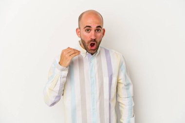 Genç kel adam beyaz arka planda izole edilmiş. Bir şeye gülüyor, elleriyle ağzını kapatıyor..