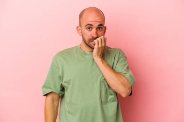 Pembe arka planda izole edilmiş, tırnak yiyen, gergin ve endişeli genç beyaz bir adam..